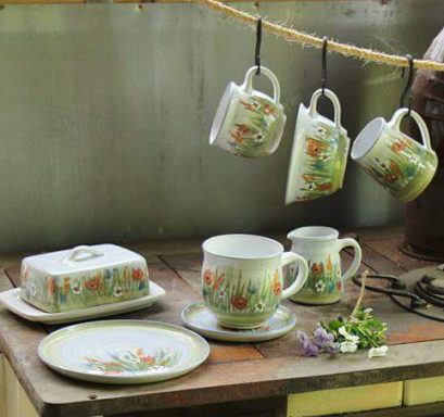 Dekor Mohnblumen Bunte Kaffeetassen und Geschirr mit floralen Motiven, an einer Leine hängend.